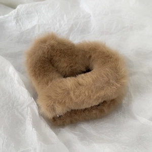 Close-up of heart-shaped plush hair claw clip with soft brown faux fur texture