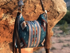 Close-up of vintage metal concho and long leather tassels on a woven bohemian shoulder bag