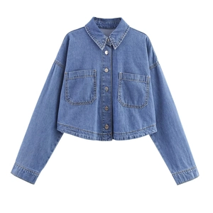 Détail d'une veste courte en jean bleu avec manches longues et poches à rabat