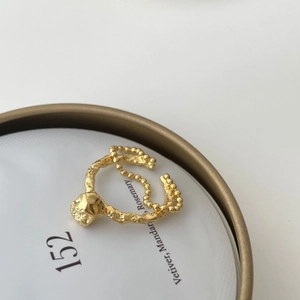 Detail of gold beaded chain ring with irregular lava texture on minimalist background