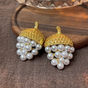 Detailed shot of vintage gold textured metal earrings with white pearl acorn clusters