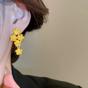 Close-up of yellow flower drop earrings with sparkling cubic zirconia on a female model