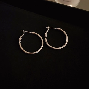 Macro shot of silver-plated geometric C-shaped hoop earrings with a polished mirror finish