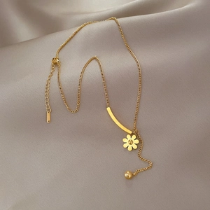 Detail of gold flower pendant necklace on champagne silk showing arc bar and bead accents