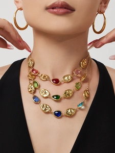 Close-up of layered 18k gold plated necklace with colorful oval stones on a model