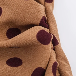 Detailed close-up of brown textile fabric featuring classic burgundy polka dot patterns