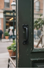 Close-up of vintage black cast iron door handle with textured finish on green wood