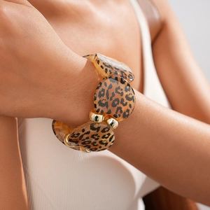 Detail shot of leopard print acrylic geometric bangle with gold metal link on female wrist