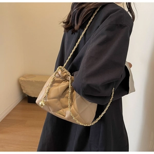 Detail of khaki quilted bucket bag with adjustable gold ball chain shown on shoulder