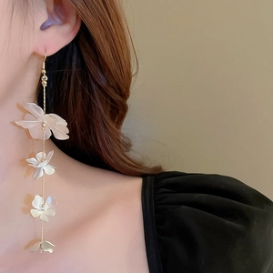 Close-up of elegant long tassel flower earrings featuring layered white petals on a model