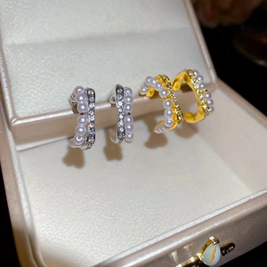 Detail of C-shaped pearl and rhinestone stud earrings in gold and silver finishes