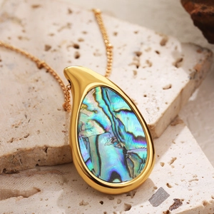 Close-up of 18k gold teardrop pendant with iridescent abalone shell inlay on stone