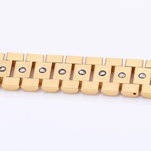 Detailed close-up of gold titanium steel watch-style bracelet with black magnetic insets