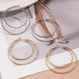 Minimalist double layered geometric gold and silver hoop earrings on a fashion magazine background