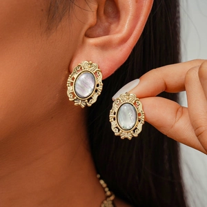 Close-up of vintage oval gold earrings with iridescent mother of pearl inlays