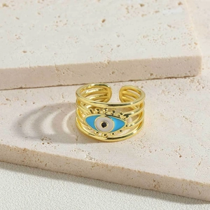 Detailed macro view of gold-plated evil eye ring on textured beige stone surface