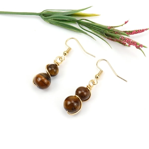 Detail of tiger eye stone earrings with golden wire wrap and cat eye luster texture