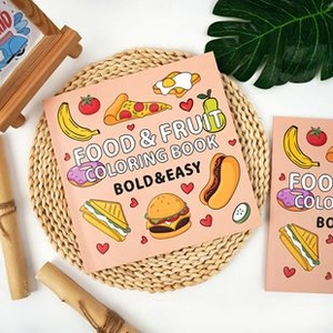 Flat lay of Food & Fruit Coloring Book on a woven mat with natural leaf decor