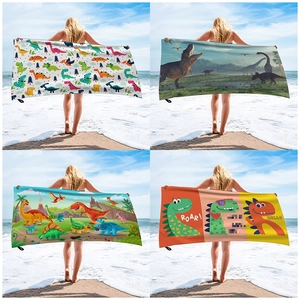 Detail view of four dinosaur print beach towels showing microfiber texture and size