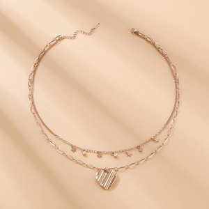 Détail du collier double couche en acier doré avec pendentifs en forme de cœur et étoile