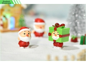 Miniature resin Santa Claus and gift box figurines in a snowy Christmas landscape scene