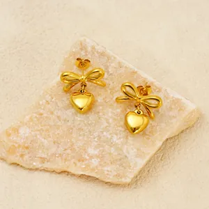 18k gold plated stainless steel bow and heart drop earrings on a natural stone base