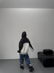 Back view of a color-block hoodie with oversized silhouette and branded ankle boots