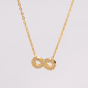 Detailed view of infinity pendant with clear zircons on a gold-plated stainless steel chain