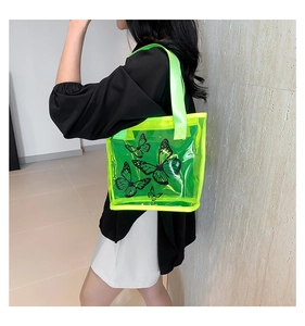 Detail of neon green transparent PVC tote bag featuring black butterfly prints and strap