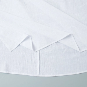 Detailed macro view of white cotton fabric showing textured crinkle weave and hem stitching