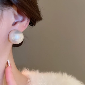 Vue macro d'une grande boucle d'oreille en perle ronde avec finition blanc nacré
