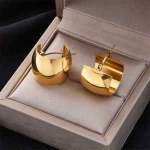 Minimalist wide golden C-shaped hoop earrings with a polished mirror finish in a jewelry box