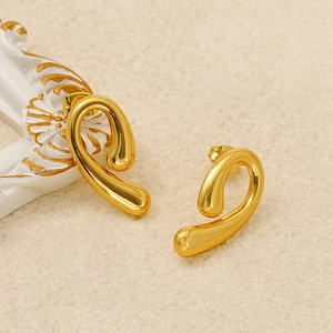 Detailed close-up of golden comma earrings with a glossy liquid metal spiral design