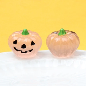 Detailed view of pink luminous resin pumpkins with smiling faces on a white plate