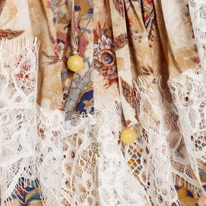 Dettaglio vestito floreale bohémien con pizzo bianco e coulisse decorate con perline gialle