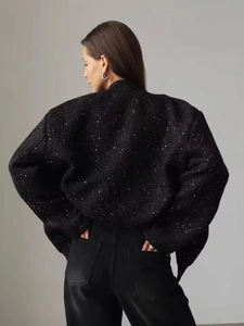 Detail of oversized black sequin jacket showing sparkling texture and structured silhouette