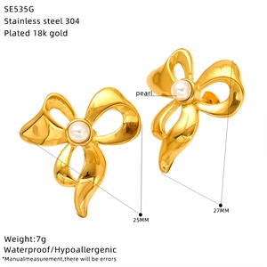 Macro view of gold-plated stainless steel bow earrings featuring a central pearl accent