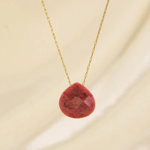 Minimalist gold chain necklace with pear-cut pink natural stone pendant on beige fabric