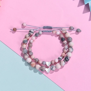 Pink zebra jasper beaded bracelets with silver heart charms on a split pastel background