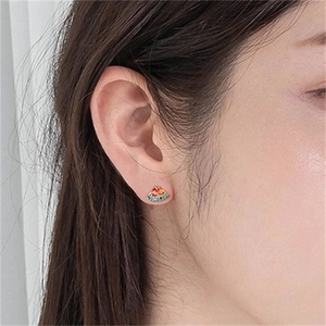 Detail of a watermelon stud earring with red and green gemstones on a model's ear