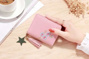 Close-up of pink PU leather zipper wallet with floral embroidery and tassel detail
