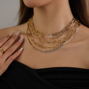 Close-up of layered stainless steel necklaces featuring paperclip and snake chains