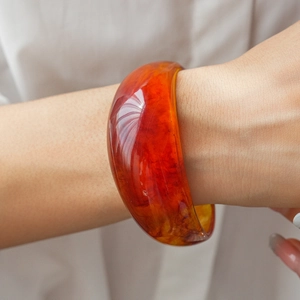 Detail of amber resin bangle showing rich marbled texture and thick round aesthetic design