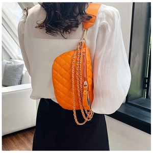 Detail of orange quilted crossbody bag with chunky gold chain and wide textile strap