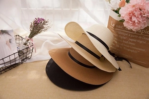 Detail of straw sun hats in multiple colors with black ribbons and natural texture