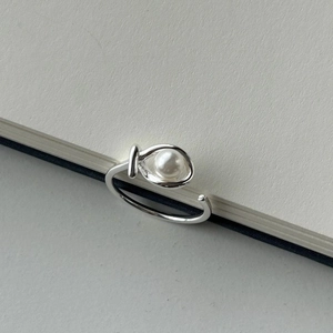 Detailed view of an S925 sterling silver pearl ring resting on a notebook edge