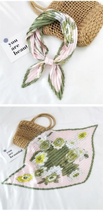 Detail of pleated silk scarf with pink and green floral patterns on satin fabric