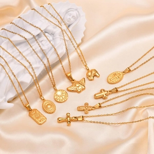 Artistic layout of golden cross and angel necklaces on champagne silk fabric background