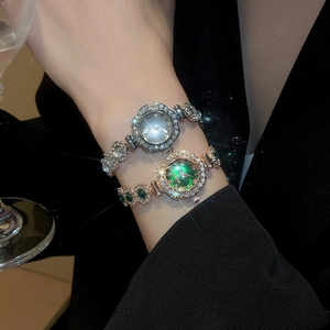Detail of luxury rhinestone floral bezel watches with emerald dial on female model wrist