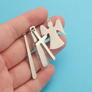 Detail shot of silver stainless steel cross and angel pendants held by hand on blue background